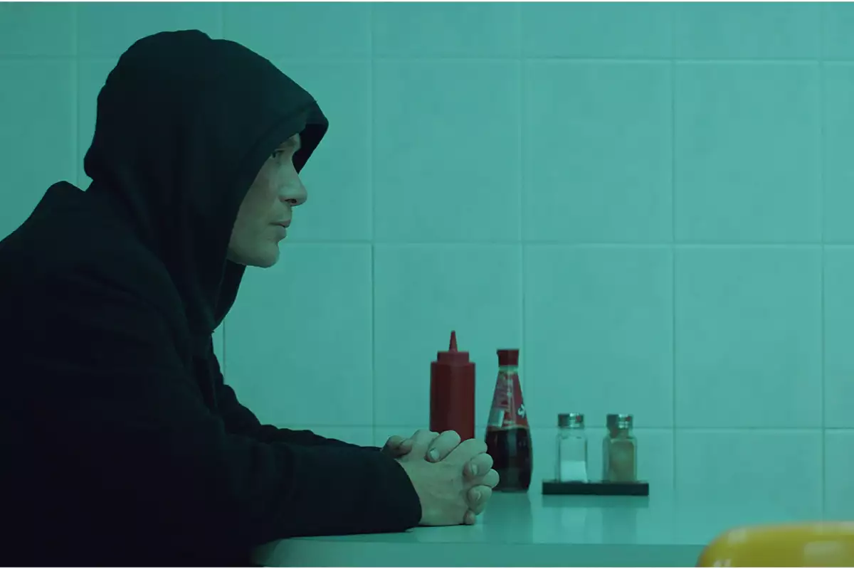 Cillian Murphey sitting in profile inside a cafe