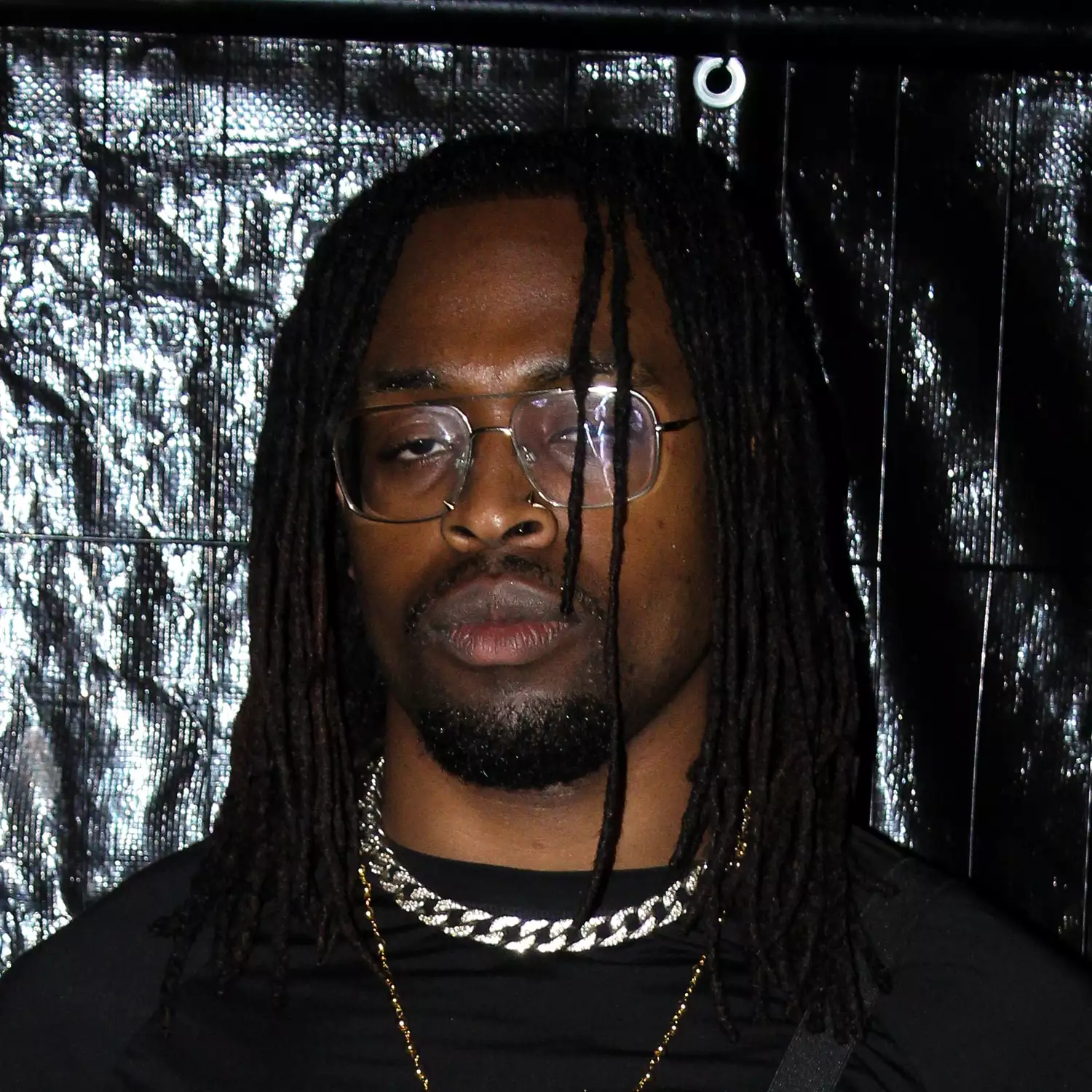 Headshot of Bill-Howell Okereke in front of a silver wall