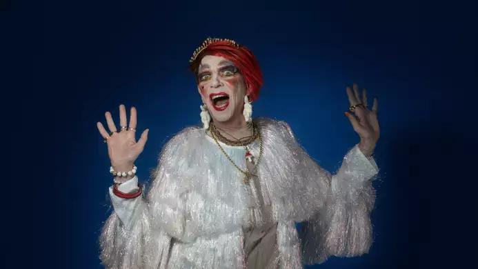 David Hoyle wearing a sparkly top on a black background