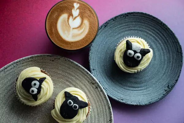 A milky coffee and three cupcakes with sheep on