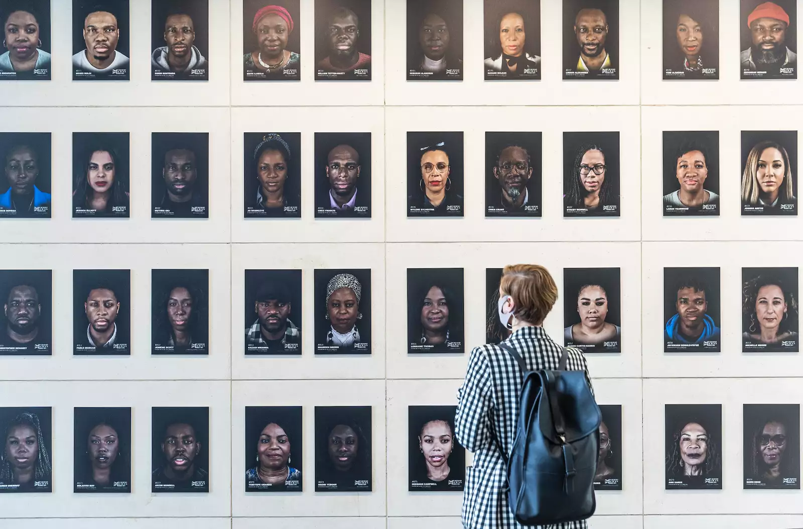 Photo of person standing in front of gallery wall of photos from Portraits of Black Britain