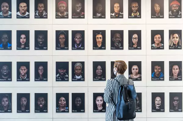 Photo of person standing in front of gallery wall of photos from Portraits of Black Britain